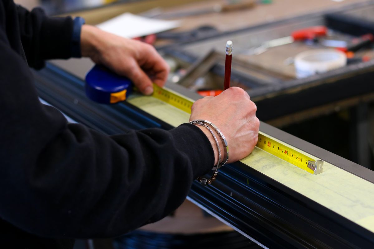 Operario midiendo y marcando un perfil de aluminio
