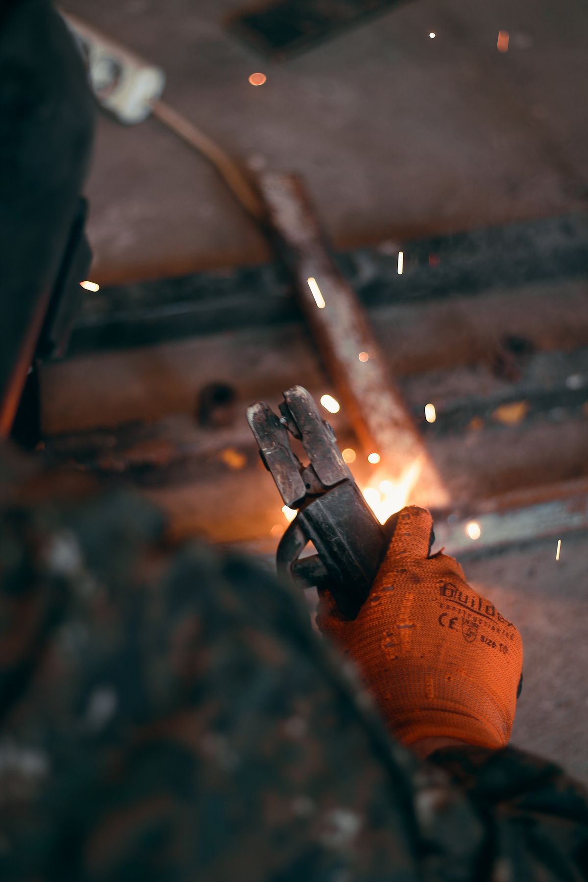 Saldatore al lavoro con scintille e dispositivi di protezione